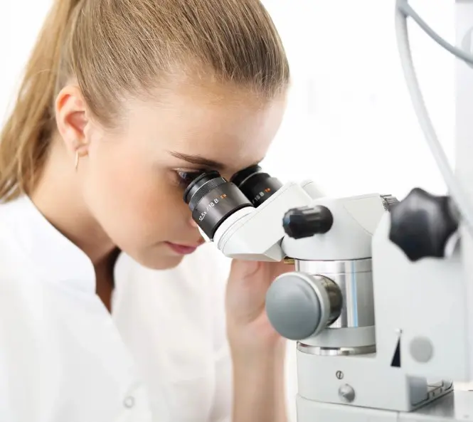 A woman looking through a microscope at something.
